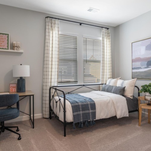 a bedroom with a bed desk and chair